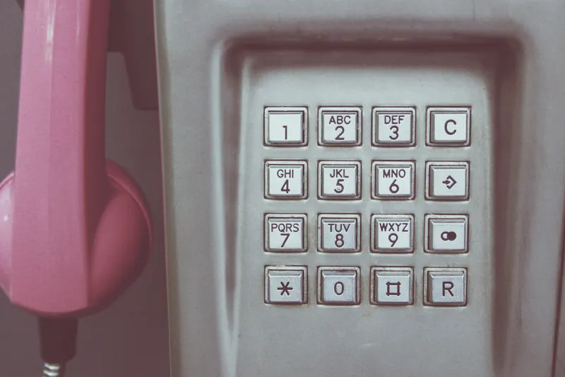 Teclado numérico de un teléfono público con auricular rosa