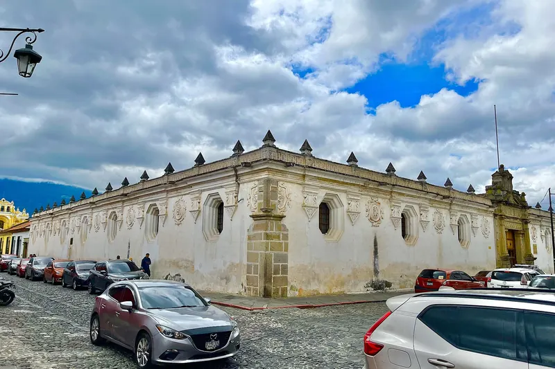 Edificio colonial de la Universidad de San Carlos en Antigua Guatemala bajo un cielo con nubes y claros azules