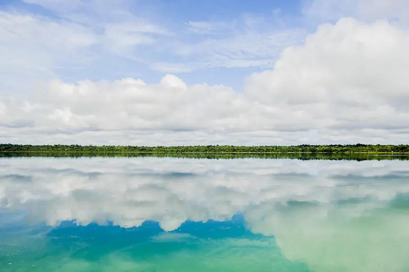 Laguna Lachuá en Guatemala con el reflejo de las nubes sobre el agua turquesa y la selva al fondo