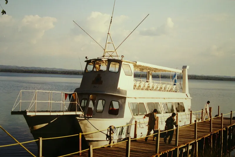 Lancha turística blanca atracada en un muelle de madera en el lago Petén Itzá, Guatemala