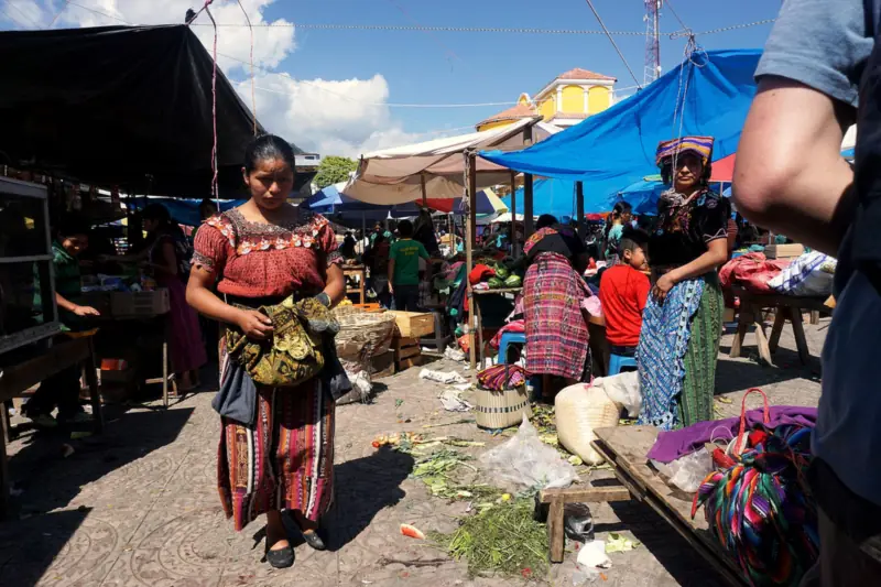 Mercado al aire libre en Santa Clara la Laguna, Guatemala, con toldos azules y vendedoras con trajes tradicionales