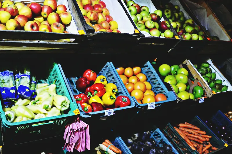 Cajas de fruta y verduras de colores ordenadas en los estantes de un puesto de venta