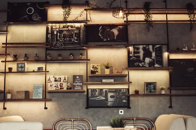 Repisas iluminadas con luz cálida en una cafetería de estilo industrial con plantas