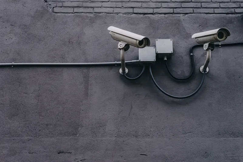 Dos cámaras de vigilancia instaladas en una pared de concreto gris