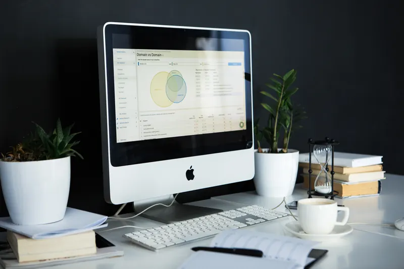 Computadora con un diagrama de Venn y tablas en pantalla sobre un escritorio con planta y fondo oscuro