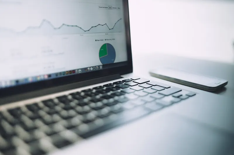 Laptop con gráficas de análisis de tráfico y un gráfico circular en pantalla, junto a un teléfono