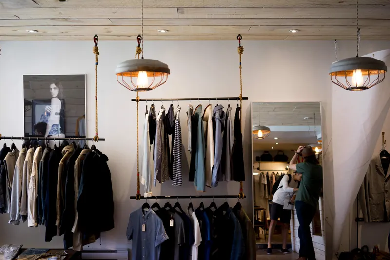 Interior de una boutique de ropa con perchas, lámparas colgantes y un espejo