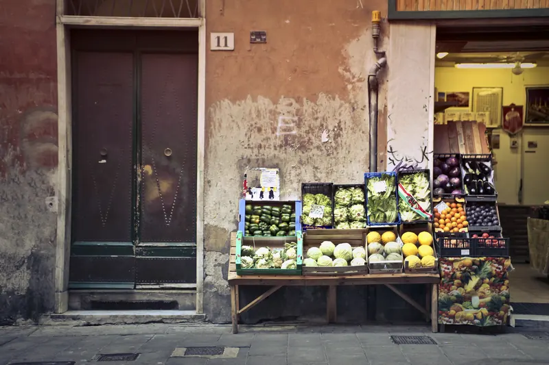 Puesto de verduras y frutas frente a una puerta antigua de madera en una pared color terracota