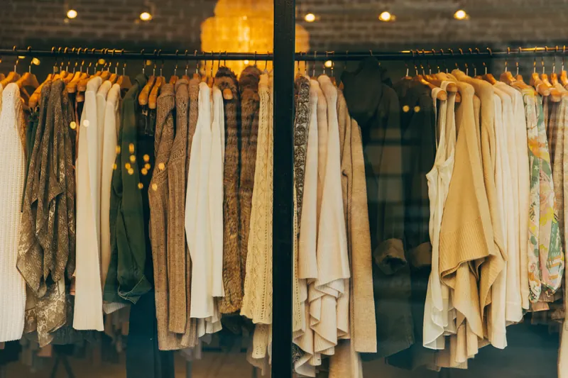 Ropa colgada en perchas dentro de una tienda con luces cálidas